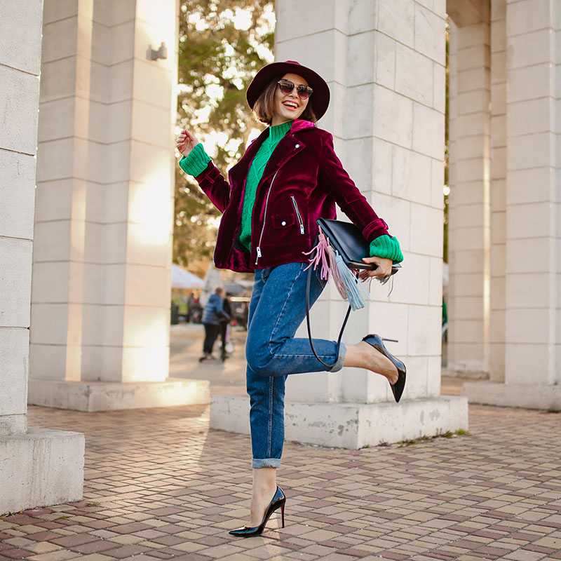 happy having fun woman in autumn style trendy outfit walking in street wearing purple velvet jacket, high heels shoes, sunglasses and hat, green knitted sweater, holding handbag